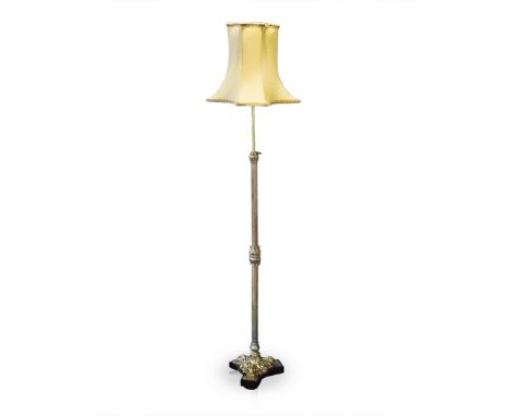 A BRASS STANDING LAMP on tapering Corinthian column support terminating in scrolling foliate tripartite foot, on a shaped woo