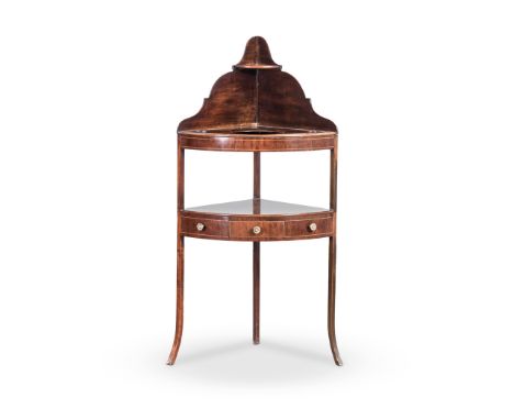 A GEORGE III WALNUT VENEERED CORNER WASHSTAND the bow-fronted top, centred by a circular aperture flanked by two smaller aper