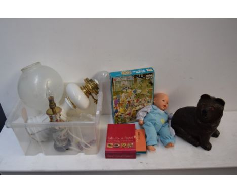 A mixed lot to include a white ceramic based oil lamp, a carved wooden bear figurine, a Cititoy doll, a set of cookery books 