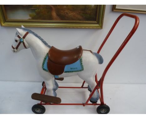 A Triang carpet toy horse on wheels with red painted handle