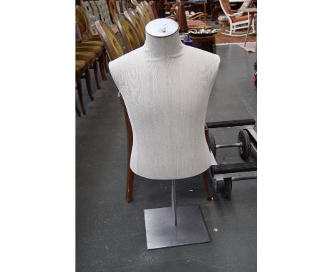 A linen covered half torso mannequin in metal stand