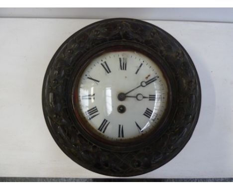 An early 20th century circular wall clock, enamel dial with Roman numerals, in an oak case carved with acorns