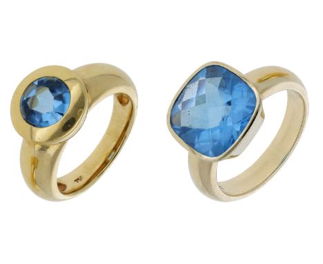 Two blue topaz rings, set with a circular buff-top and cushion-shaped blue topaz respectively, first stamped ‘750’, second st