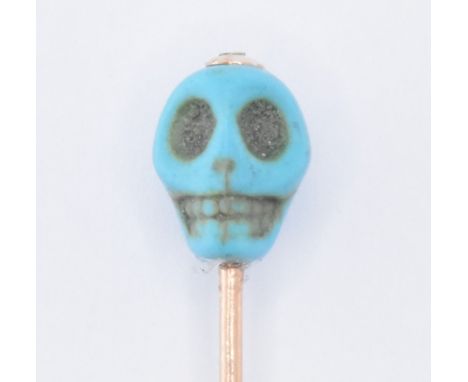 A 19th Century Victorian 14ct gold and turquoise skull stick pin. The pin having a carved turquoise skull finial on a rose go