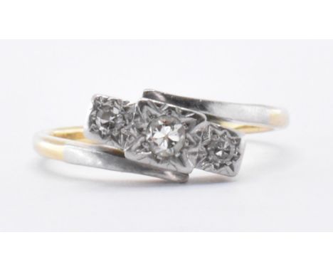 An 18ct gold &amp; platinum three stone diamond crossover ring. The ring having three graduating round cut diamonds illusion 