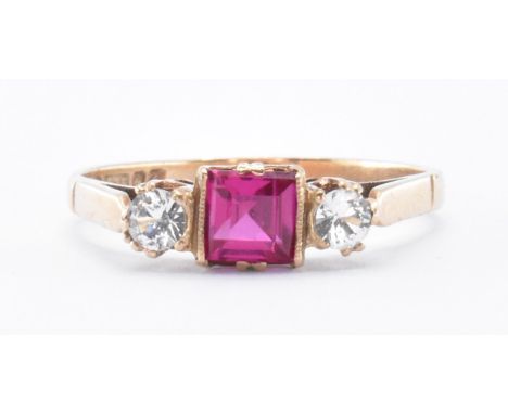 A 9ct gold hallmarked three stone synthetic ruby and CZ ring. The ring having a central emerald cut synthetic ruby flanked by