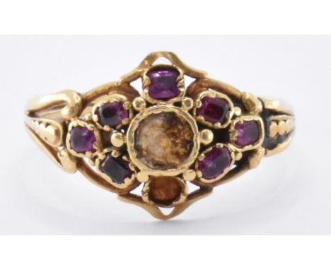 An 18th Century George III gold and ruby cluster ring. The ring being set with seven flat cut rubies (two missing), with pier