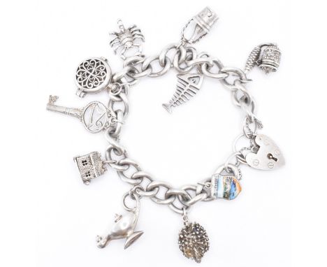 A vintage silver hallmarked charm bracelet having a curb link chain with a heart lock clasp. The bracelet having ten charms i
