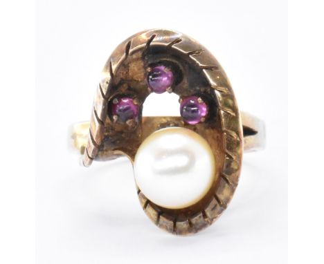 A 14ct gold ruby and pearl cocktail ring. The ring set with a central pearl having ruby cabochon accents in a cupped mount. M