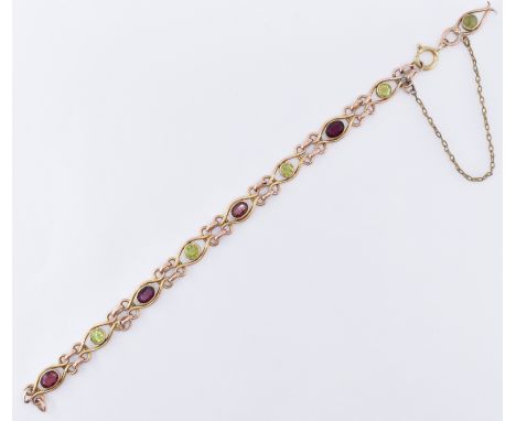 A vintage 9ct gold bracelet being set with alternate round cut peridots and oval cut garnets. The stones set within gold scro