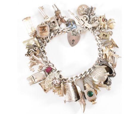 A vintage mid 20th Century silver hallmarked charm bracelet having a heart padlock with a curb link bracelet chain, adorned t