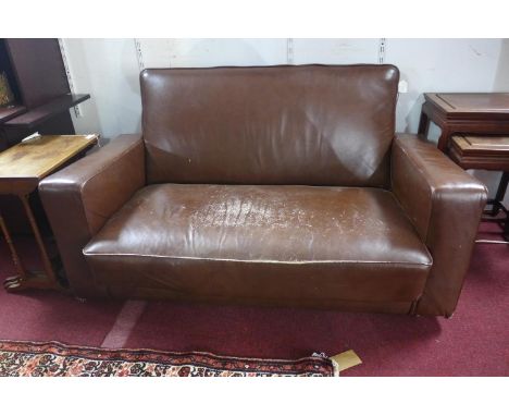 An early to mid 20th century brown leather sofa, raised on castors 