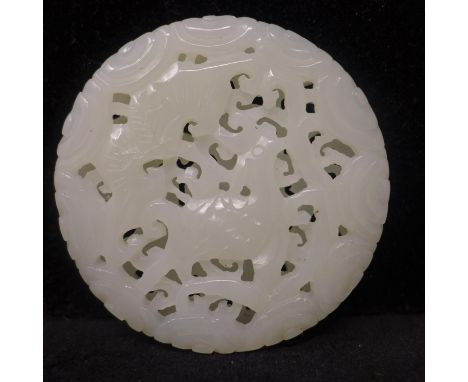 A Chinese celadon jade circular pendant, carved and pierced decorated with bats and deer, 5cm 