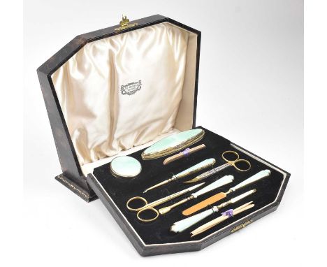 A cased George V hallmarked silver gilt guilloche enamelled manicure set. The lot to include a hallmarked silver gilt trinket