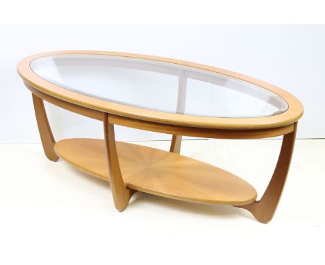 Mid Century teak coffee table of oval form with inserted bevelled glass top, four curved supports and lower tier shelf. Measu