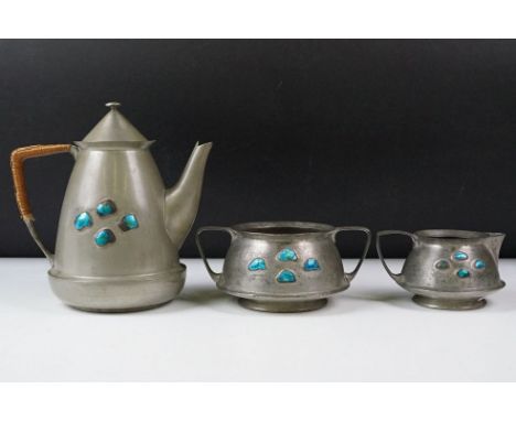 An early twentieth century pewter tea set with peacock enamel decoration in the style of archibald knox. 