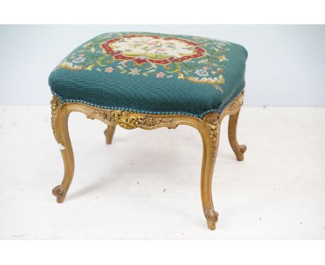Continental stool, with woolwork panel top, the carved sections decorated in gold, on carved cabriole legs, 40cm high x 50cm 