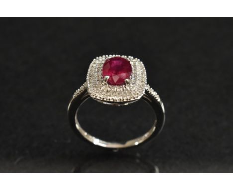 A ruby and diamond cluster ring, central oval red ruby, surrounded by a double stepped frame encrusted with fifty nine round 