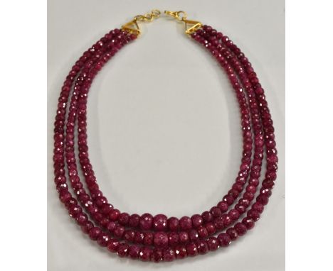 A three strand faceted ruby bead necklace, three tapering graduated strands of pinky red rubies ranging from approx 4.7mm to 
