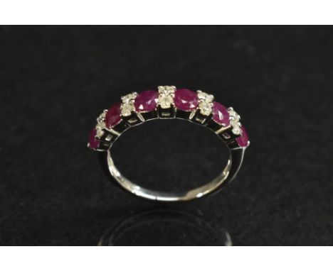 A ruby and diamond semi eternity ring, linear set with six red round cut rubies, each divided by a pair of brilliant cut diam