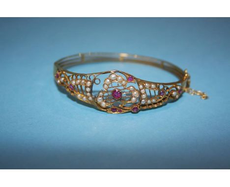 A yellow metal bangle, decorated with garnets and seed pearls, 12.1g