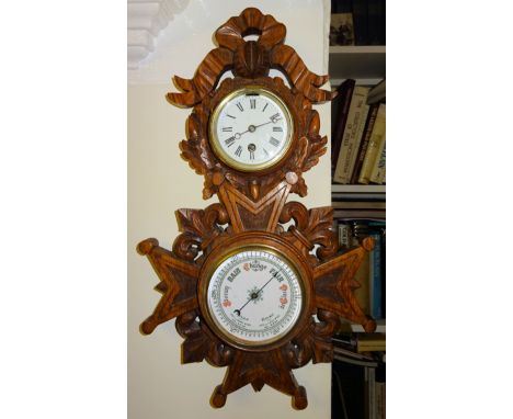 An early 20th Century aneroid Barometer and timepiece in a carved oak frame with acorns fleur de lis etc.  19" (49cms) high. 