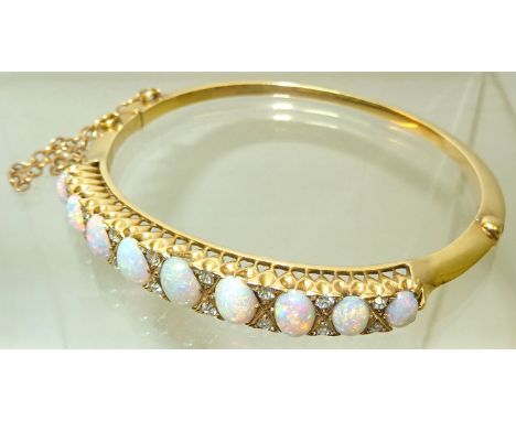 A gold Bangle set with nine oval cabochon cut white opals and with sixteen diamond spacers, not marked but tests as 15ct.