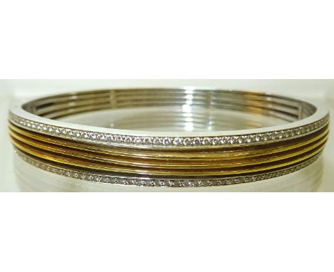 A two colour gold Bangle set with a double row of 57 round brilliant cut diamonds divided by three individual rows of polishe