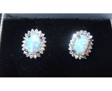 A pair of silver Earrings each with an oval opal and cubic zirconias.