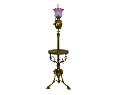 Late 19th/early 20th Century gilt brass floor standing oil lamp, now converted to electricity, the reservoir with lion mask d
