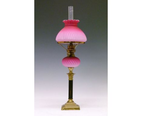 Victorian oil lamp having a small pink satin glass reservoir with wrythened decoration, standing on a reeded wooden pillar wi