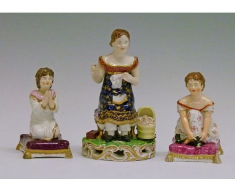 19th Century Derby porcelain figure depicting a young woman seated, sewing, a book on her lap and a baby in a cradle beside h