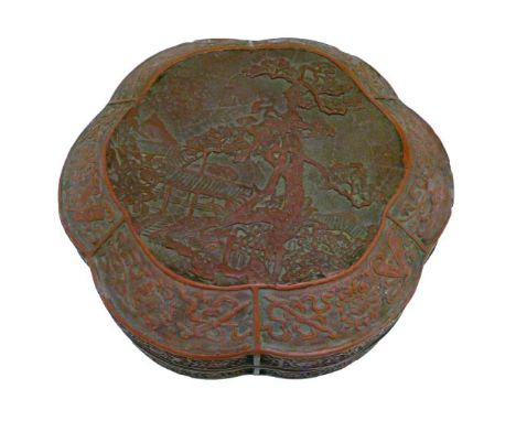 Antique Chinese cinnabar lacquer shaped circular box and cover, having central relief decoration depicting buildings in a lan