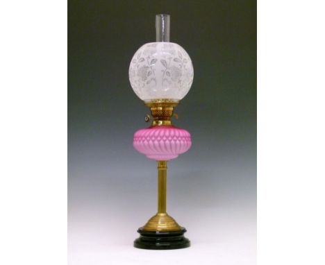 Victorian oil lamp having a pink satin glass reservoir, reeded pillar and circular foot on a black glazed earthenware base, w