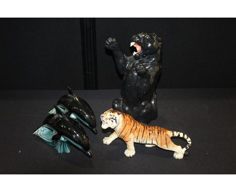 Decorative panther figure, 36cm high, together with a tiger and a pair of Poole pottery dolphins, (4)