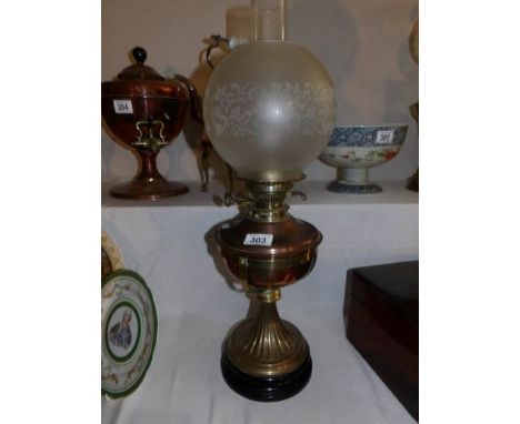 A brass oil lamp with black pottery base and acid etched shade