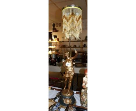 A figural table lamp with beaded shade