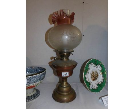 A brass oil lamp with etched shade