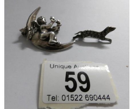 A silver cherub on moon brooch and a silver dog brooch