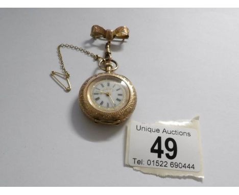 An early 19th century 14ct gold ladies fob watch in chased gold with enamel face and surmounted by ribbon with safety chain i