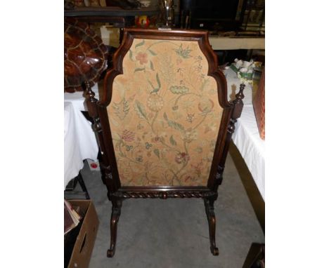 A mahogany fire screen with embroidered panel