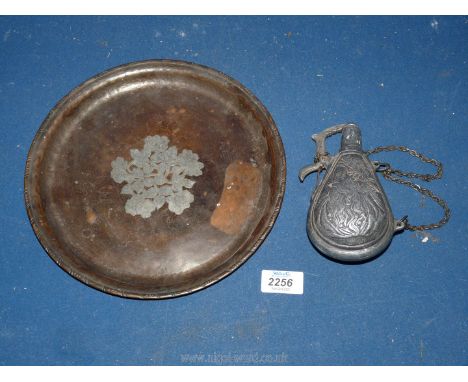 An embossed copper plate and a pewter gun powder flask.