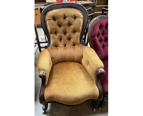 A Victorian mahogany framed lady's chair with a button back upholstered spoon back with pad arms and seat on cabriole legs an