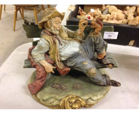 A Capodimonte figure of a tramp on a bench with a squirell signed B. Merli.  