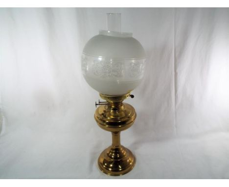 A free standing brass oil lamp with glass shade