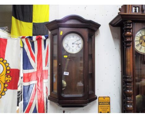 A decorative polished wood-cased wall clock, the case with opening glazed door, revealing the benefit of internal trinket she