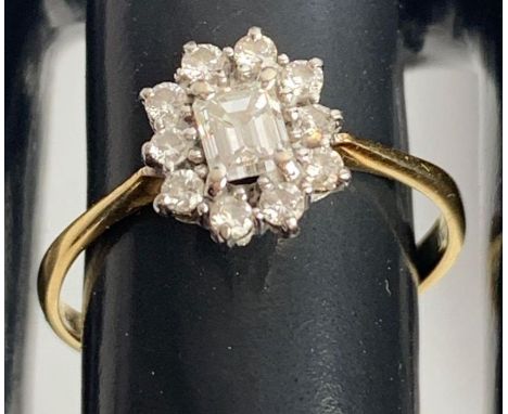 An 18 carat gold diamond cluster ring, the central step cut diamond of approximately 0.35 carats, enclosed by ten brilliant c