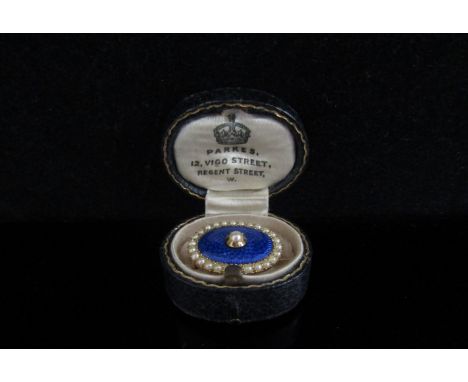 A memorial brooch with blue enamel front centrally set with single pearl framed by seed pearls, verso inscribed "In memory of
