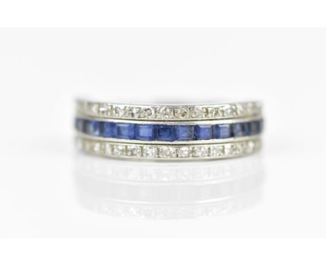 A white metal, diamond and sapphire half eternity ring, with a central row of sixteen step cut pave set sapphires between a r
