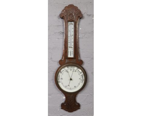 A carved oak banjo barometer with ceramic dial.  Crack to thermometer and surround.